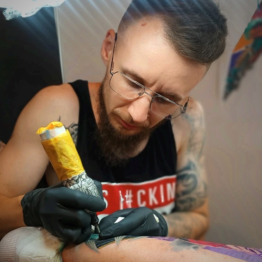 Jakub DINKZ Chruściel pracuje nad kolorowym tatuażem